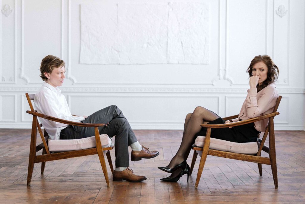 Man and woman sitting on chairs during a quiet conversation about emotional intelligence in romance. 
