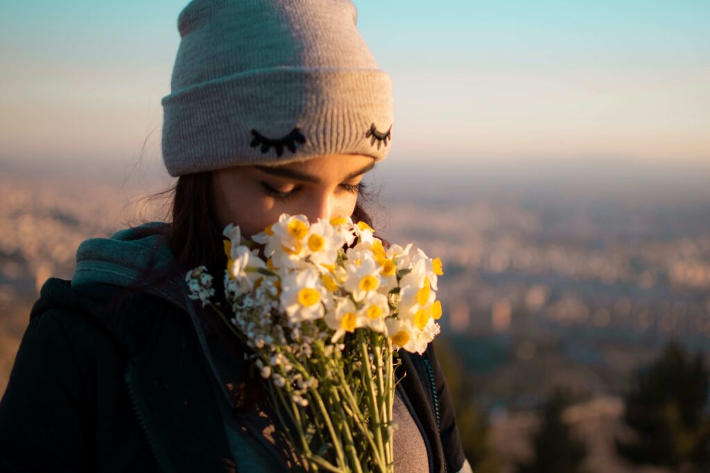 Self-Worth Quotes: 50 Powerful Reminders to Know Your Worth in Love A woman wearing a beanie smelling flowers reflecting self-worth quotes and personal self-respect.