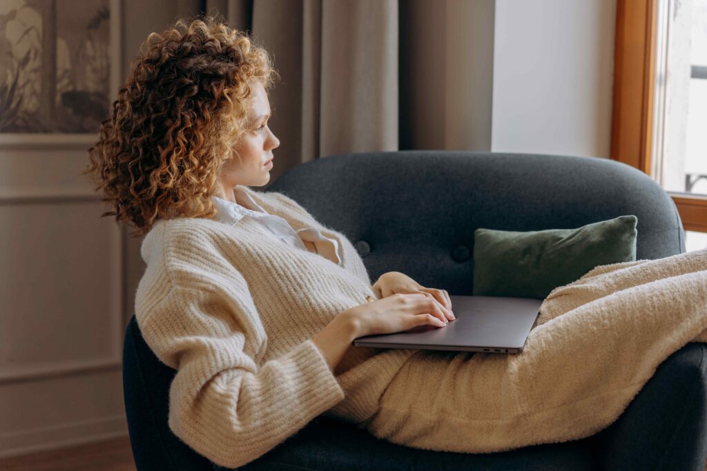 A thoughtful woman in an armchair reflecting on relinquishing personal identity during marriage.