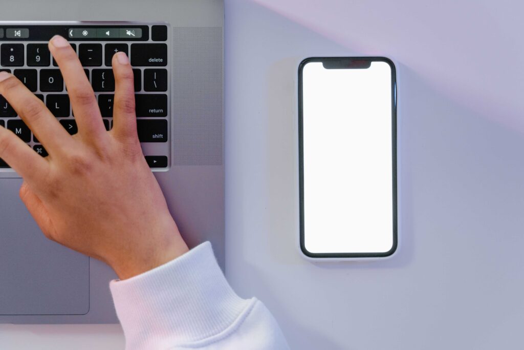 Hands typing on a laptop next to a phone during a quiet fade-out from unsupportive peers. 