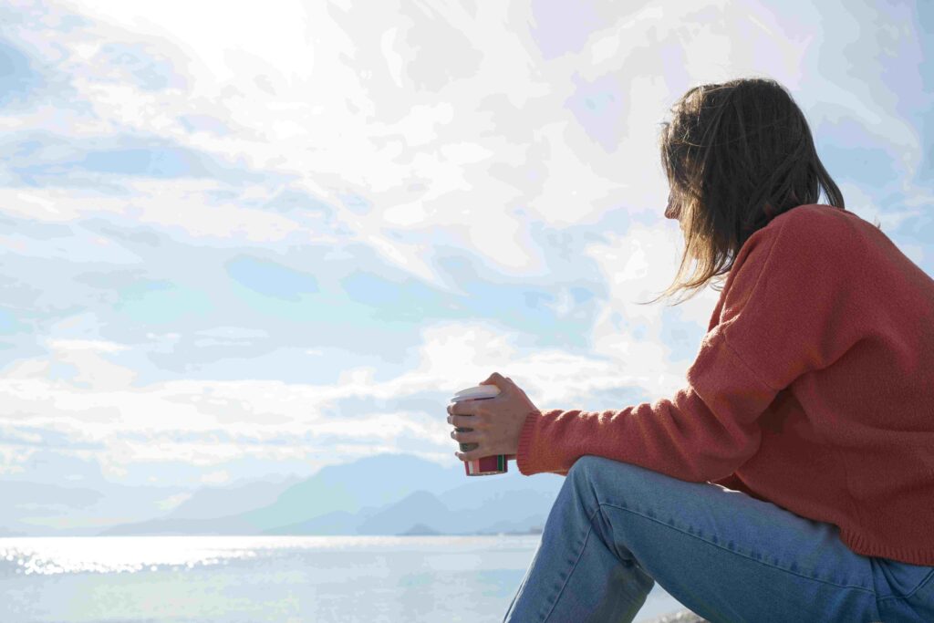 A lonely person sitting at the edge of a pier feeling drained by insincere friendships.