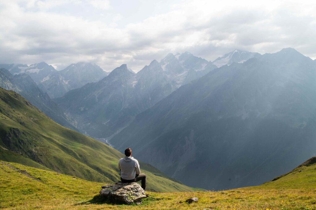 A person sitting on a mountain peak realizing time heals all emotional wounds is a myth. 