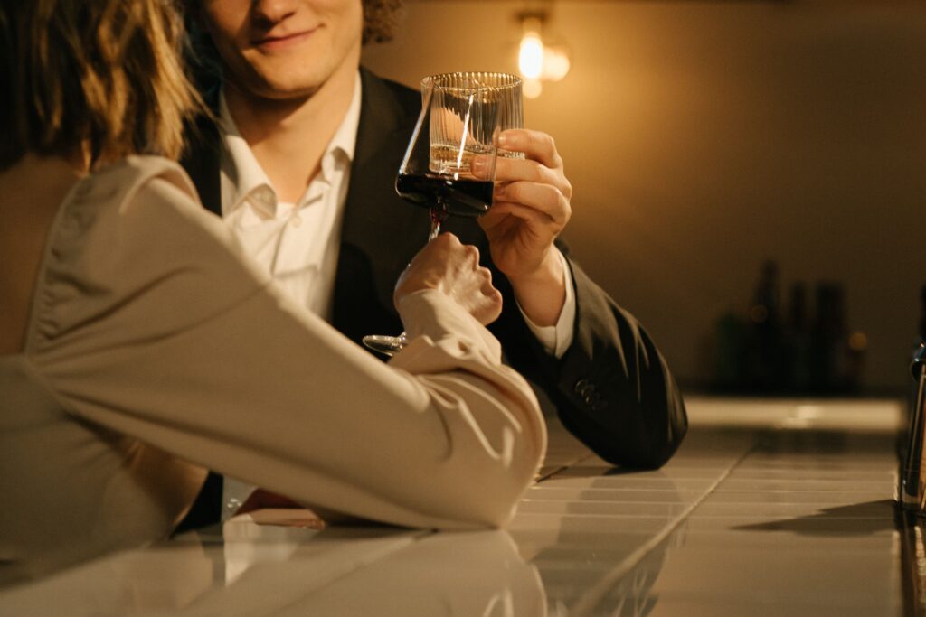 A charming man clinking glasses with a woman illustrating what is a womanizer in dating.