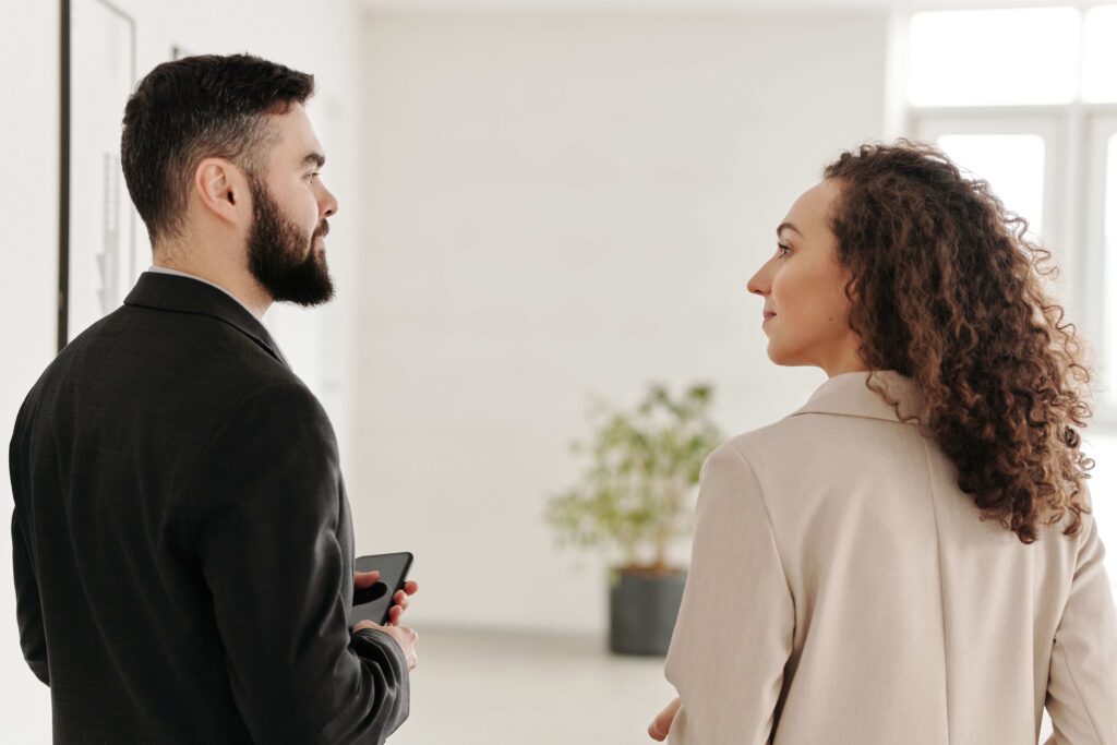 Two colleagues standing in office discussing what is a work wife relationship.