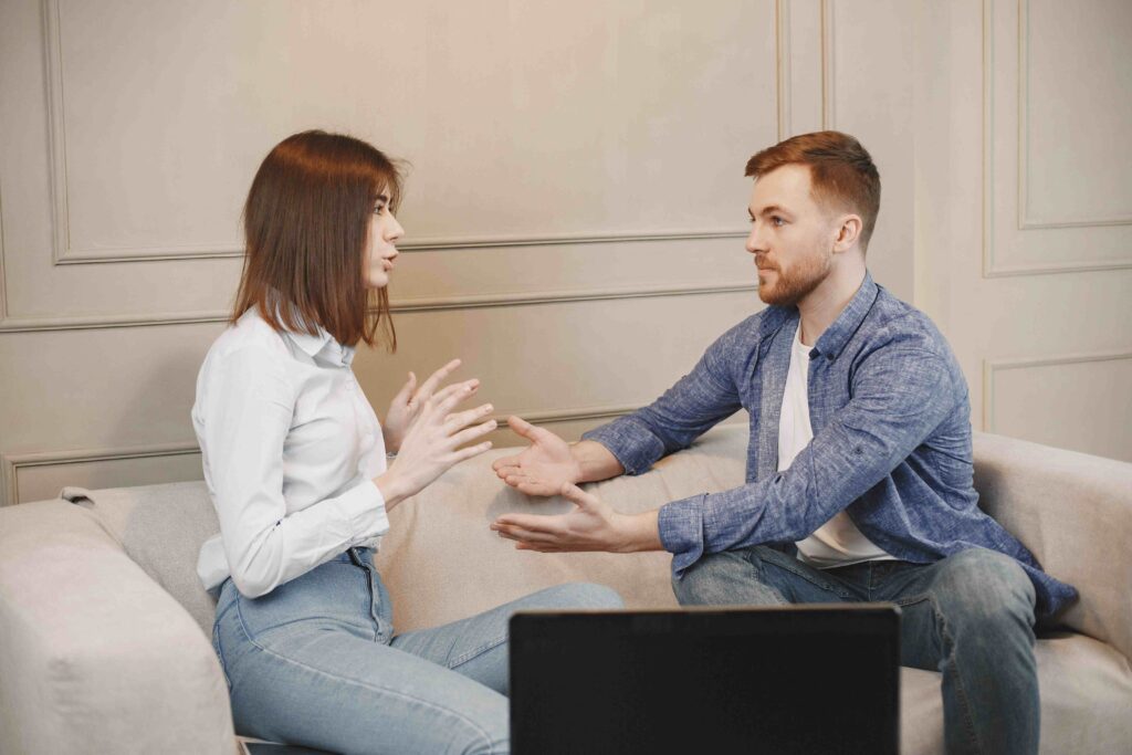 A couple having a serious conversation on the couch discussing office spouse dynamics. 