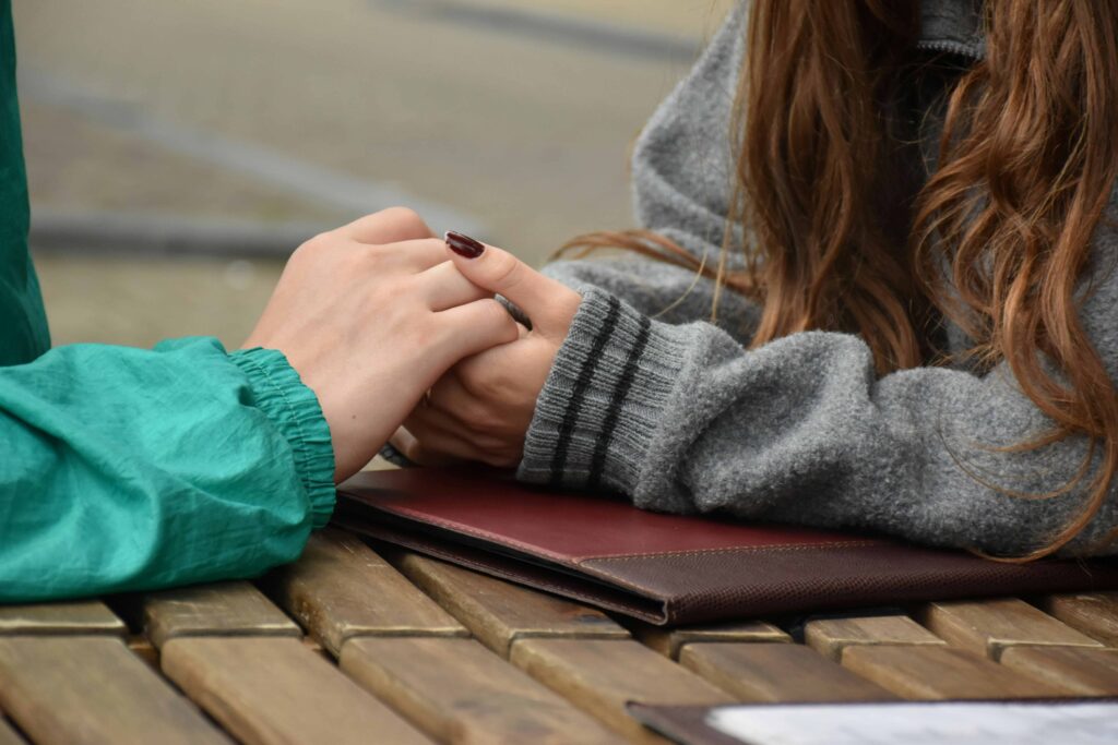 Two people holding hands gently over a notebook while identifying verbal lies calmly. 