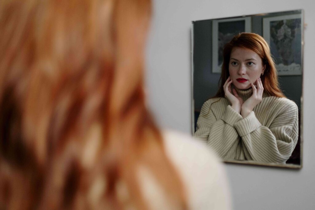 A woman looking in the mirror reflecting inner validation and unapologetic self assurance.