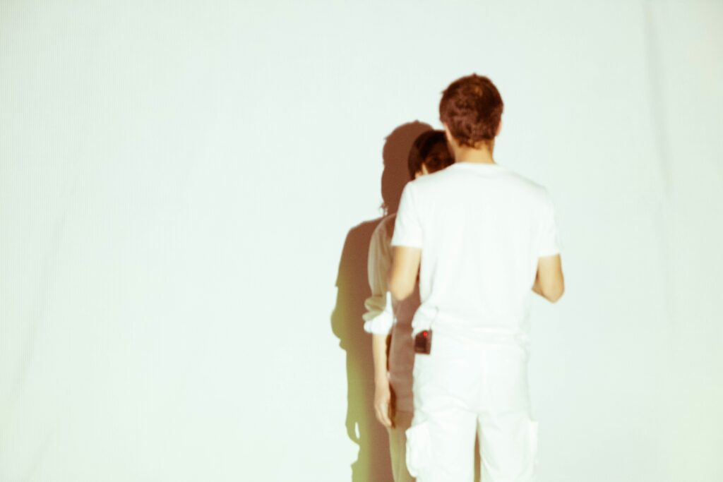 A man and woman standing against a light wall reflecting on intense dream scenarios in love. 