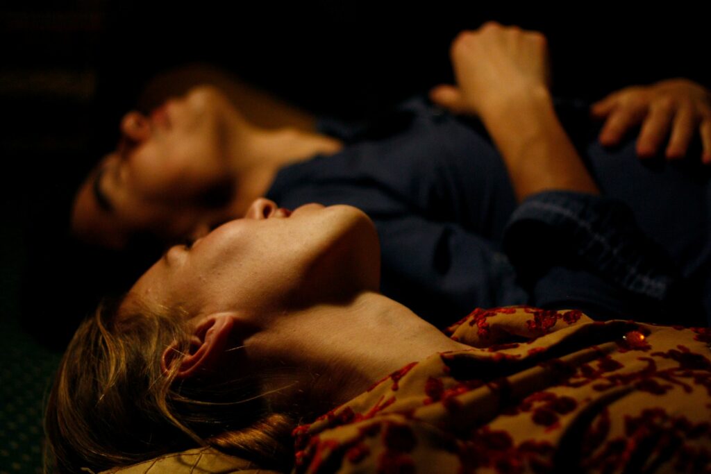 A couple lying on the floor in low light practicing self awareness in relationships.