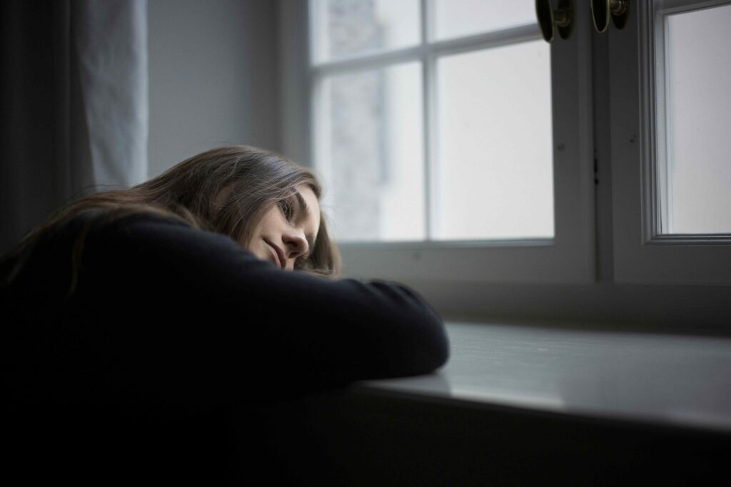 A thoughtful woman resting her head by the window showing conscious feelings.