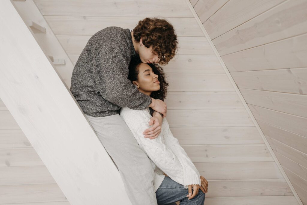 A man gently kissing his partner head on stairs reflecting opposite temperament dating.