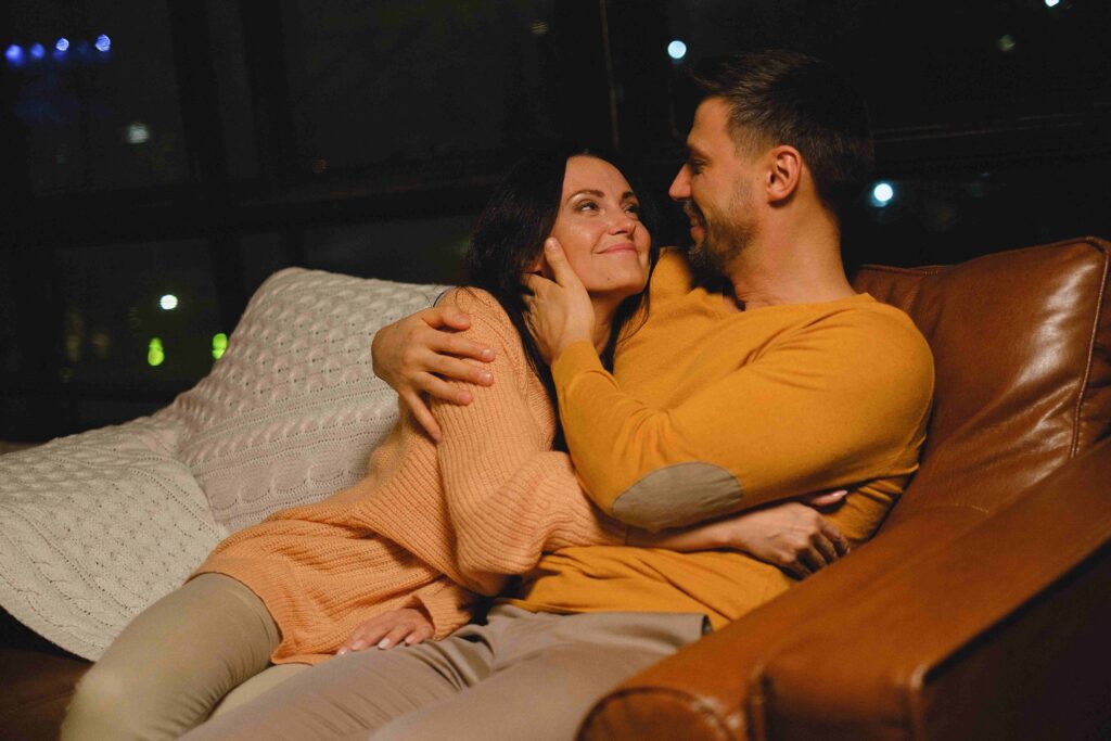 A man gently hugging his partner on an armchair showing somatic communication in love.