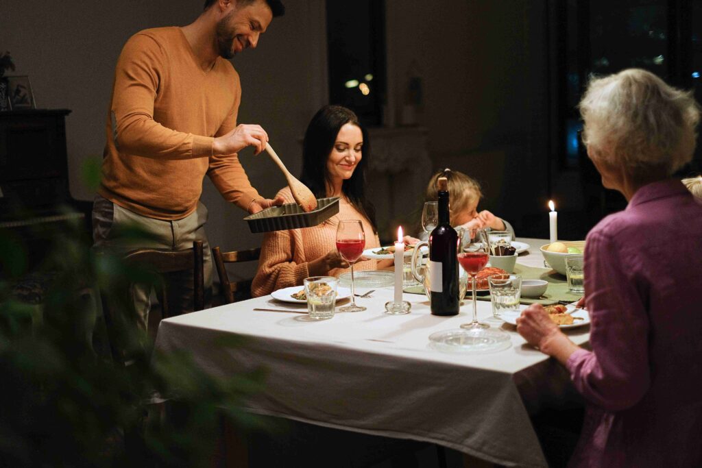 A married couple serving food at the family dinner table practicing boundary setting with mother.