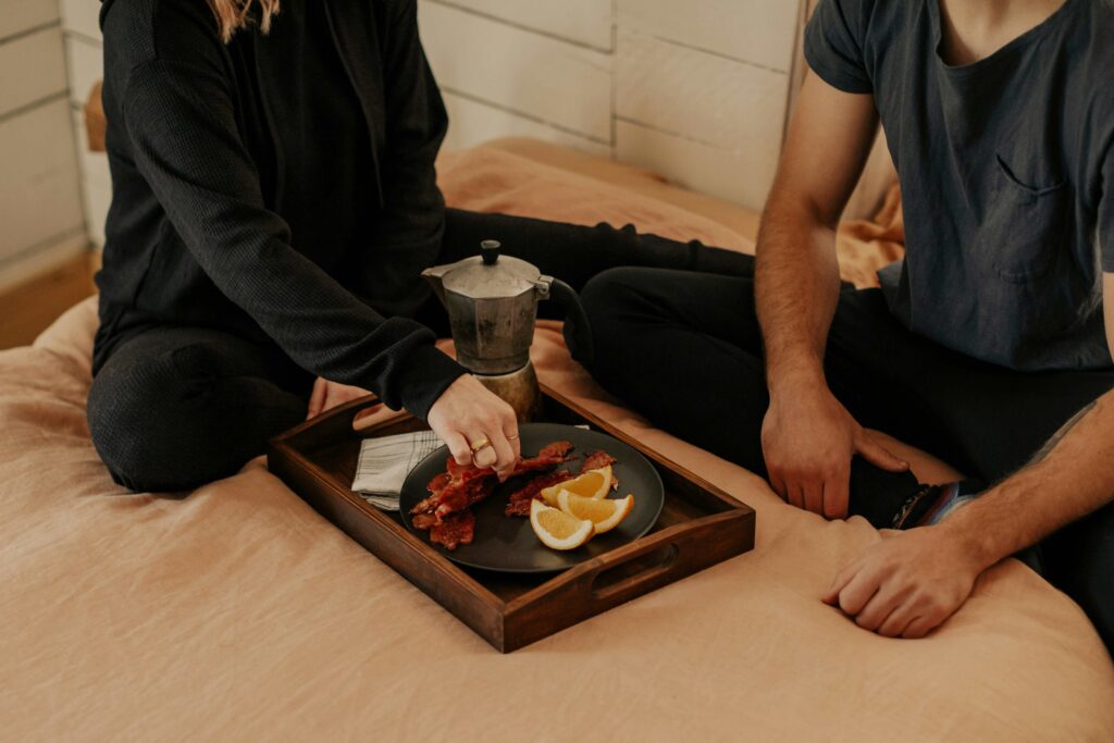 A couple sitting on bed sharing breakfast and overcoming emotional distance.