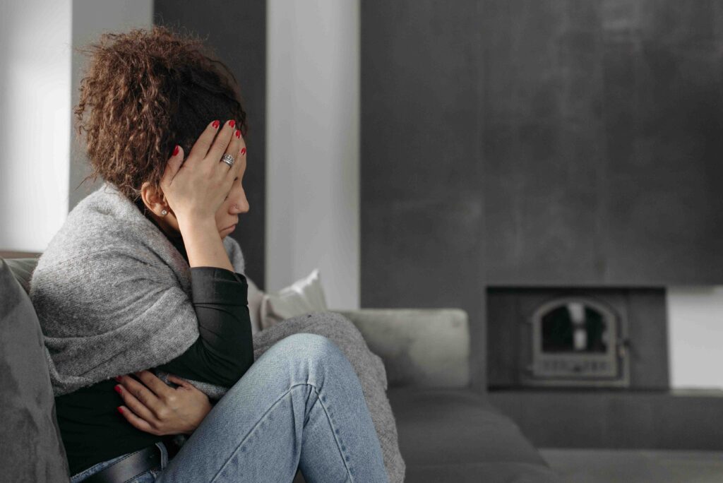 Intrapersonal Intelligence: The Key to Healing Toxic Relationships A distressed woman holding her head on the sofa reflecting on intrapersonal intelligence.