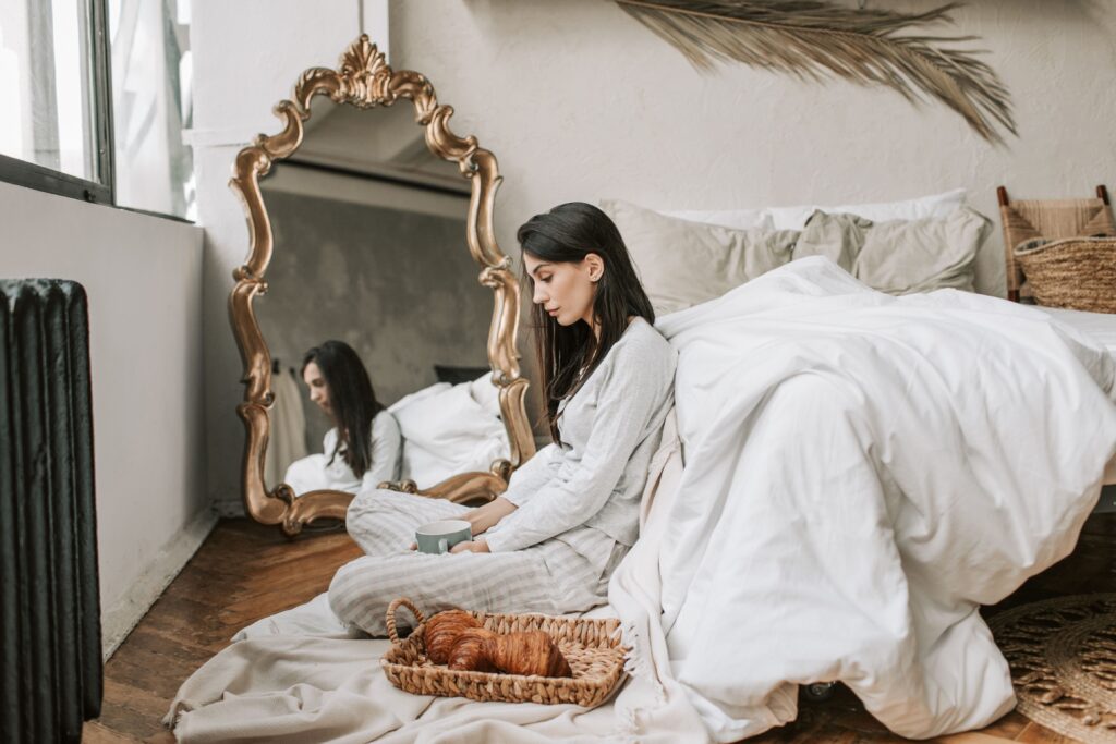 A thoughtful woman sitting on the floor by a mirror practicing multiple intelligences theory.