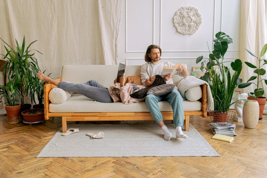 Naturalistic Intelligence: Creating a Calming Sanctuary for Your Marriage A relaxed couple reading together on the couch surrounded by plants practicing naturalistic intelligence.