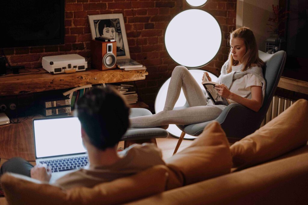A couple working and relaxing in cozy living room with soft lighting enjoying a calming home environment.