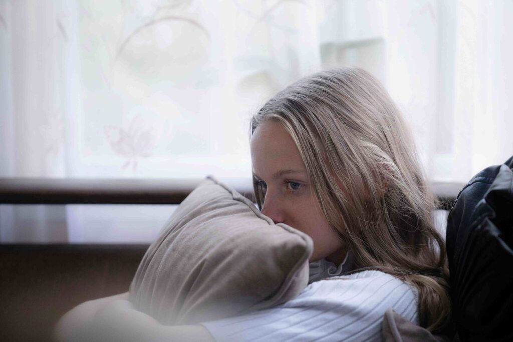 A woman resting head on a pillow indoors reflecting on maternal emotional manipulation.