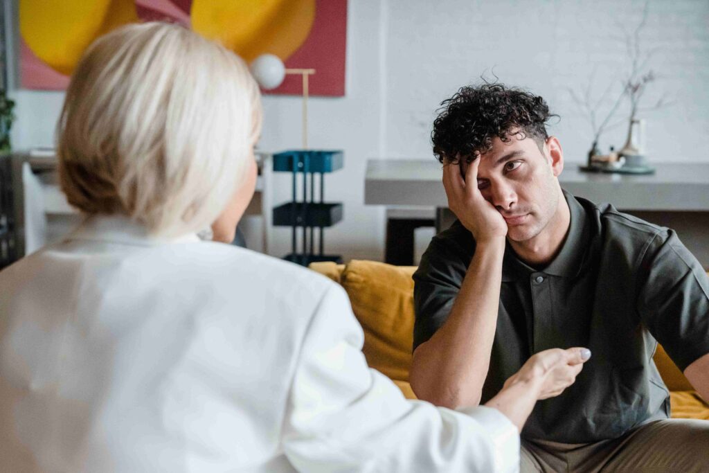 A stressed young man listening to his mother illustrating dysfunctional parenting patterns.