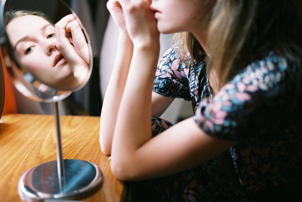 A woman looking into a table mirror analyzing avoidant relationship patterns and self defense.