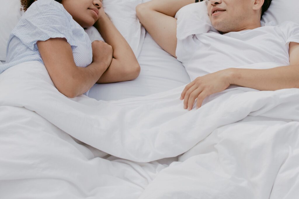A couple lying peacefully together in a white bedroom experiencing nature based stress reduction.