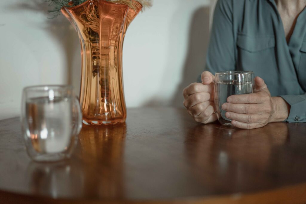 Close up of hands holding a glass on table illustrating barrier defense and spotting deception cues. 
