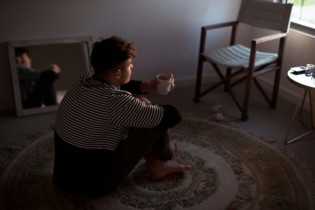 A lonely man sitting on the floor holding coffee showing emotional unavailability impact.