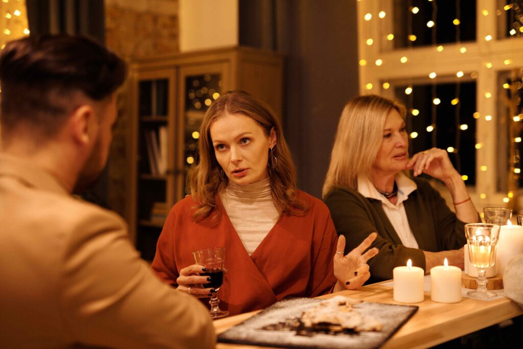 A woman speaking forcefully at dinner displaying controlling daughter-in-law traits.