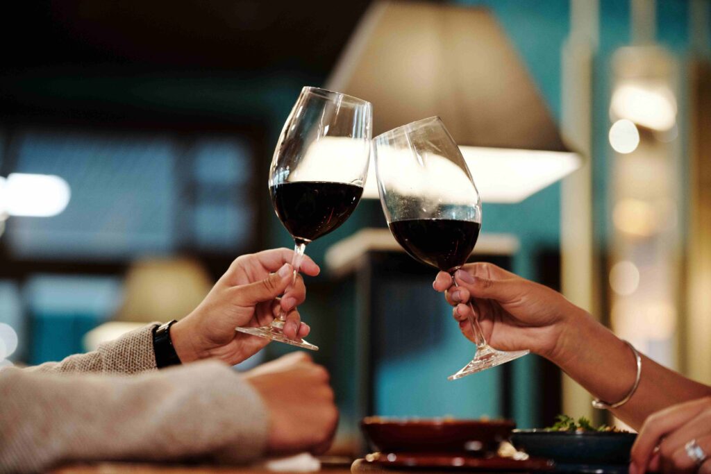 Two people toasting red wine glasses reflecting meaningful reasons why you love someone.