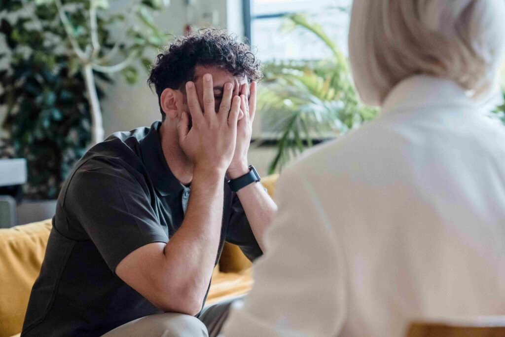 Toxic Mother: 8 Signs You Were Raised by a Narcissistic Mother A distressed adult child covering face with hands showing the emotional impact of a toxic mother.