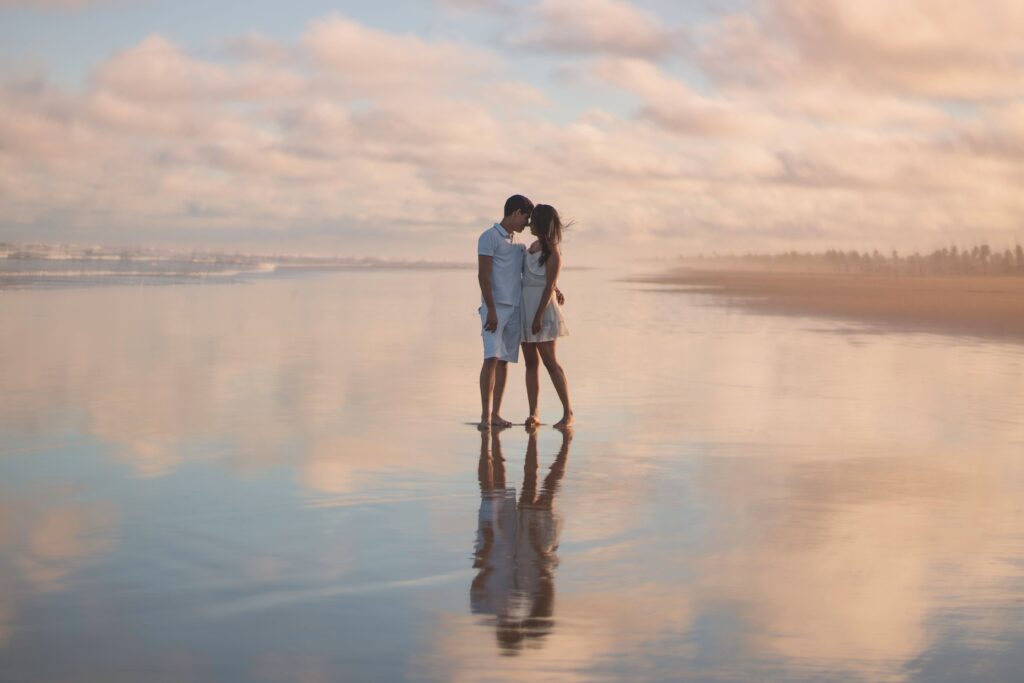 Types of Intelligence: How They Secretly Shape Your Love Life A romantic couple standing on a wet reflective beach illustrating types of intelligence in love.