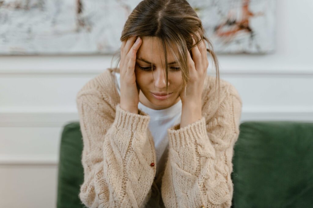 A stressed woman holding her head showing mental strain from detecting dishonesty signs.