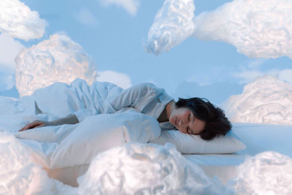 A woman sleeping peacefully surrounded by cloud props exploring vivid dreams meaning.