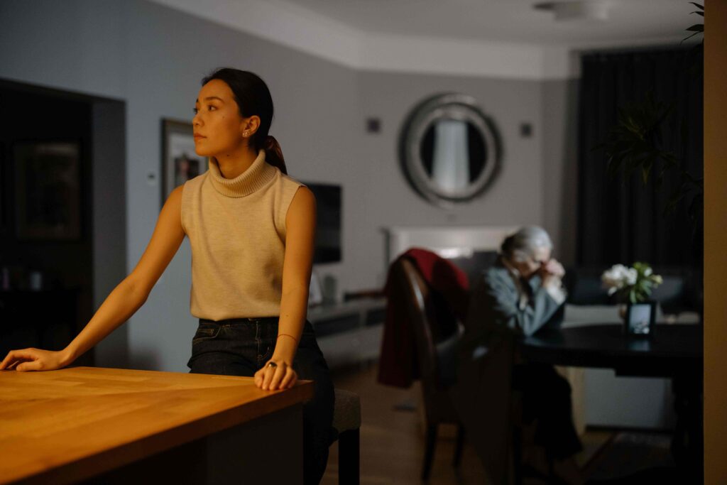A woman standing alone in living room reflecting on controlling parents behavior.
