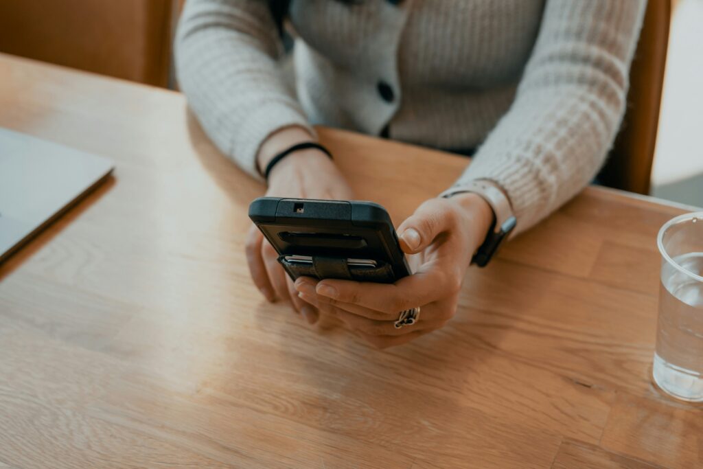 Close up of hands holding phone at desk avoiding emotional flooding triggers in arguments.