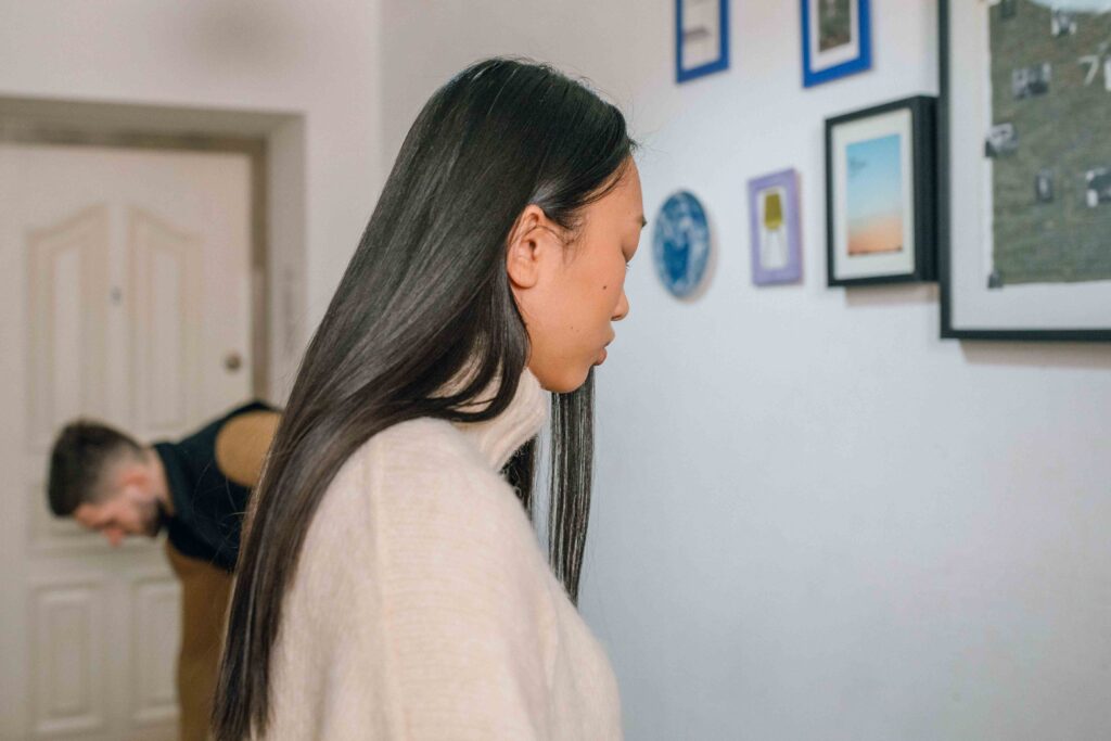A woman standing quietly while a man looks away reflecting verbal communication skills.