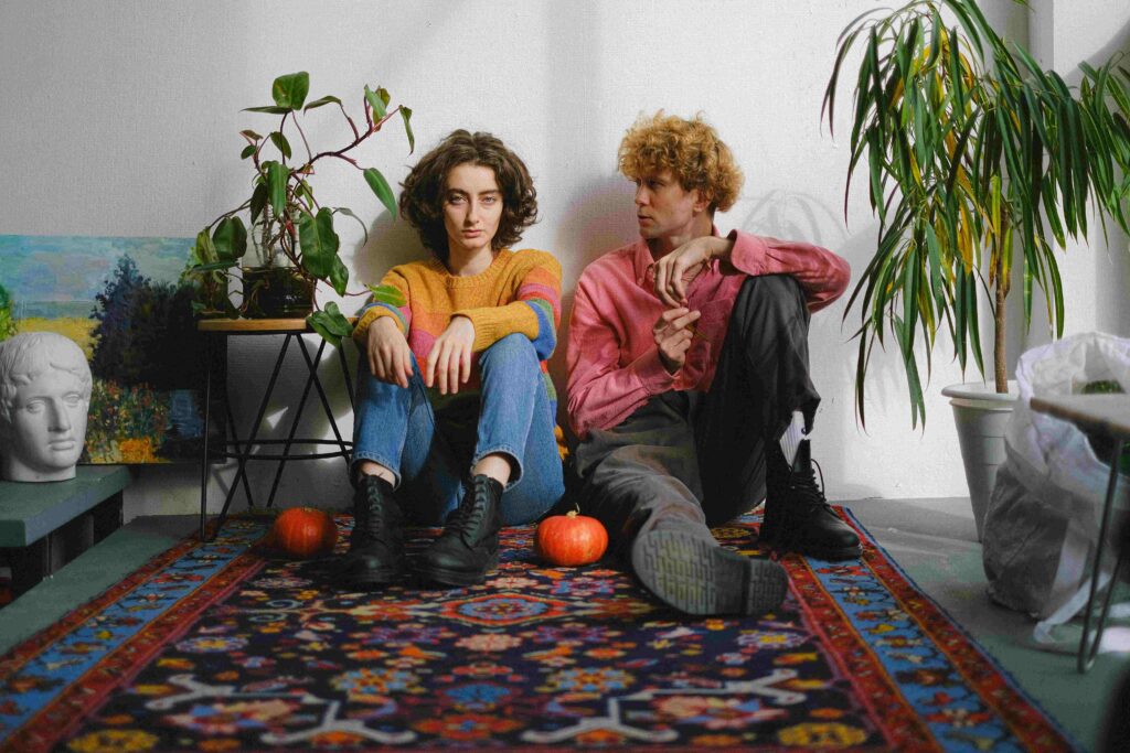 A couple sitting on carpet near plants portraying an introvert extrovert relationship dynamic.