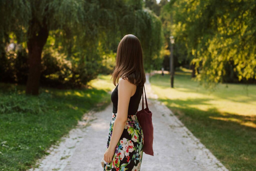 A woman walking down a path in park reflecting subconscious warning signs in love.