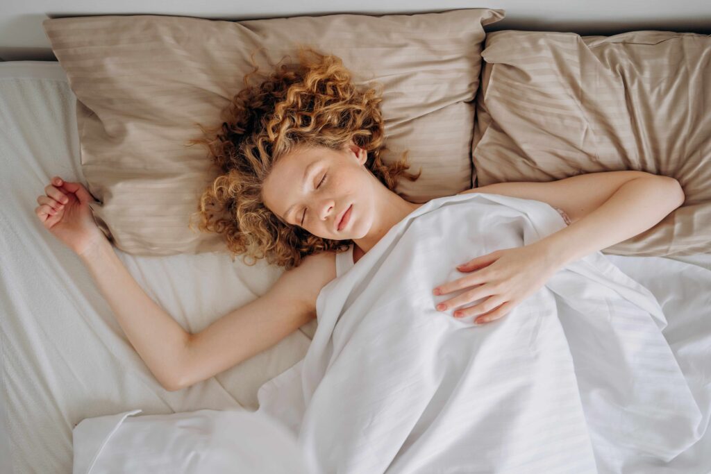 How Long Do Dreams Last? The Science of Emotional Healing During Sleep A woman sleeping under white sheet in bed discovering how long do dreams last.