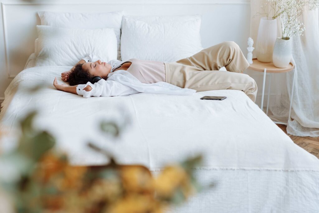 A relaxed woman lying across bed in comfortable clothes tracking dream duration stages.