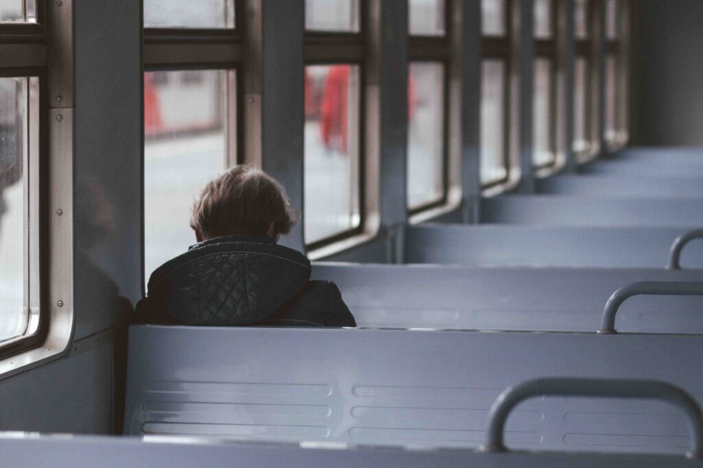 A lonely person sitting in an empty train car reflecting on the thought i have no friends.